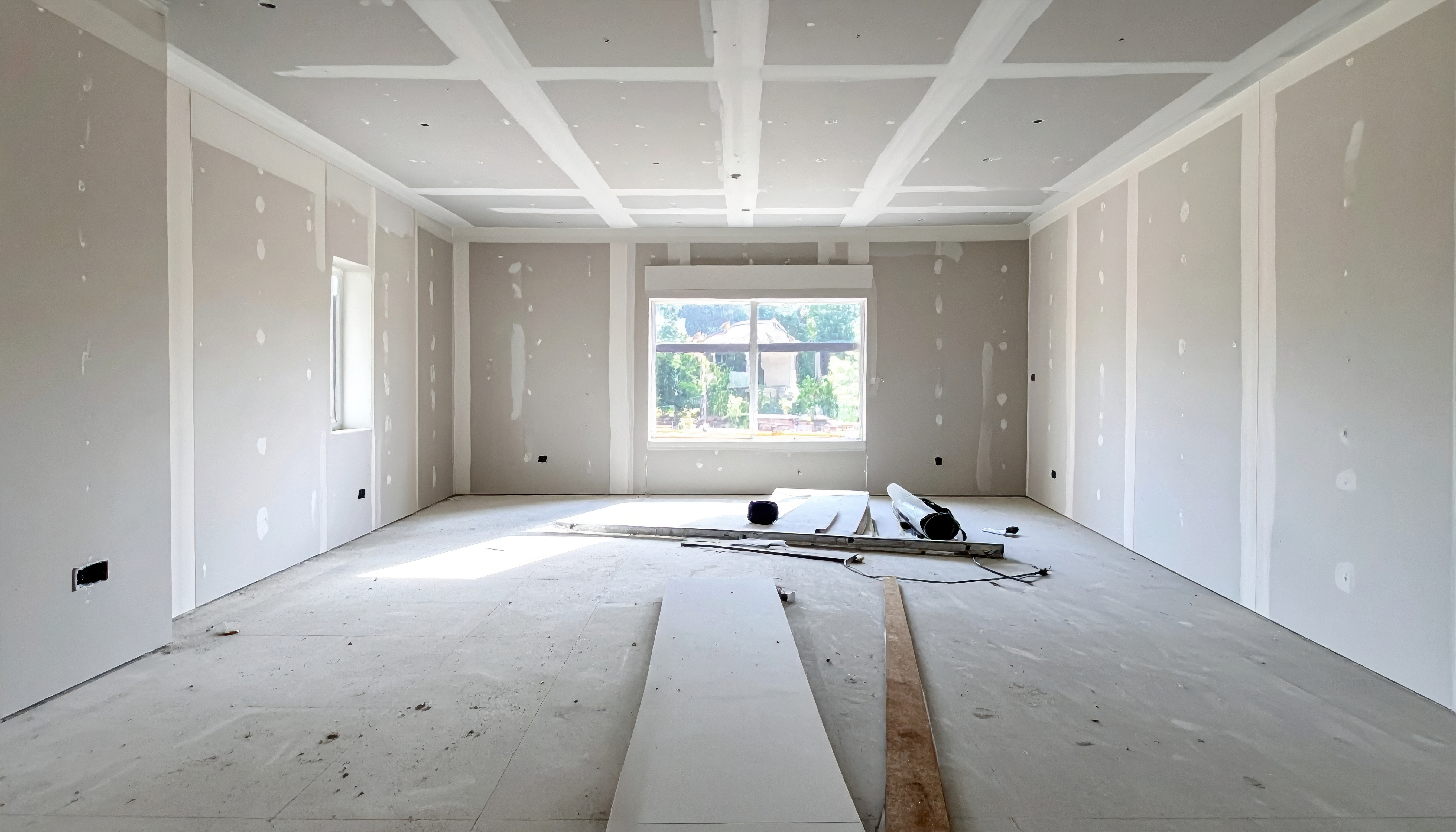 Interior room mid-conversion with fresh drywall and a large window